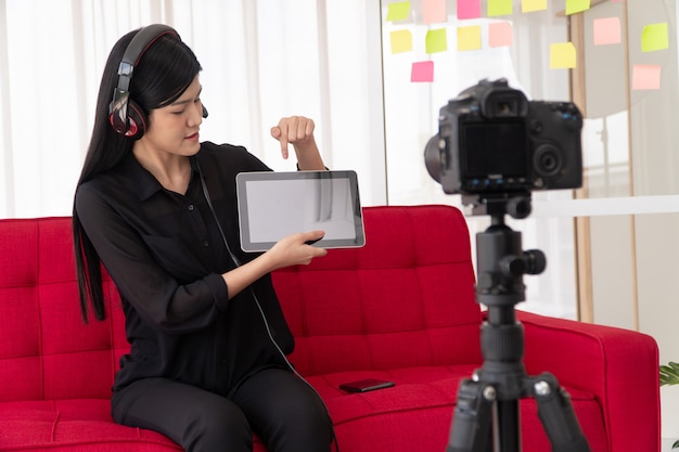 Vlog Aziatische vrouw blogger influencer zittend op de bank in huis en video blog opnemen voor het lesgeven en coachen van haar studenten