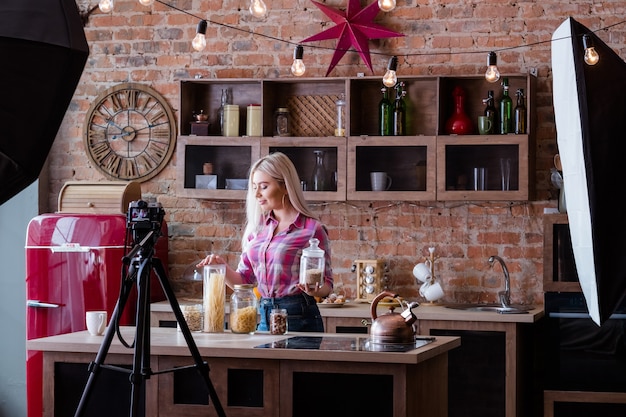 Foto vlog over voeding. koken. zolder keuken studio. backstage fotografie. blonde jonge vrouw met potten.