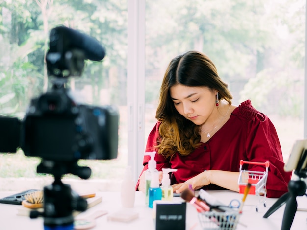 Le belle donne di vloger usano internet online per rivedere la sua marca di cosmetici