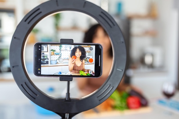 Foto vloggen en freelance job concept food blogger bereiden voedsel koken en culinair vaardigheden concept jonge vrouw schiet video met camera op statief