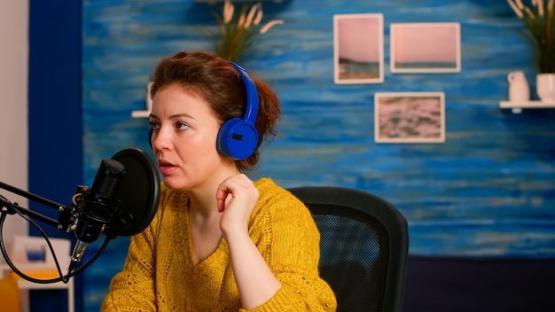 Vlogger controleert microfoongeluid met vinger en begint met livestreamen terwijl je in de thuispodcaststudio zit