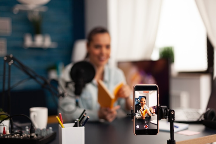 Foto vlogger houdt boek vast tijdens podcastreview op sociale media. beïnvloeder van creatieve inhoud die live video streamt en digitale communicatie via sociale media opneemt voor haar publiek