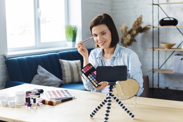 Vlogger testing eyeshadow and broadcast live video to social network at home.