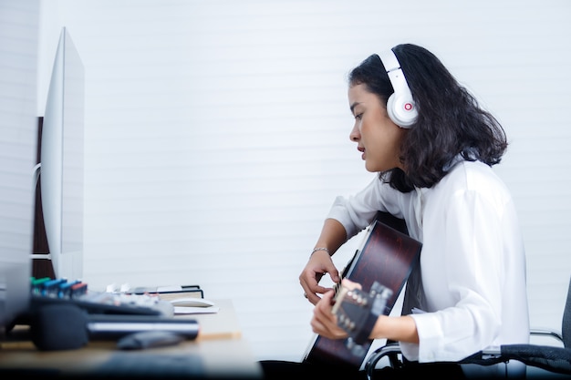 vocalist Wearing Headphones plays guitar recording a song in digital studio