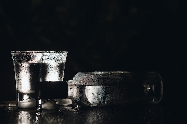 Vodka in shot glasses on dark background.