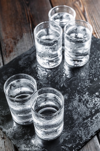 Vodka in shot glasses on rustic wood 