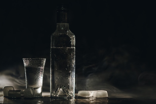 Vodka shots with ice on black table, copy space