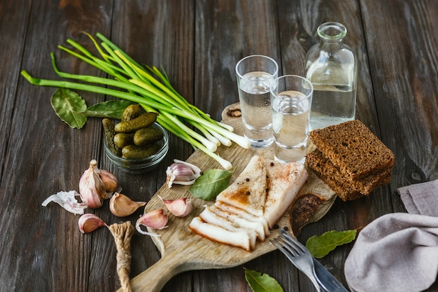 Vodka and traditional snack on wooden wall