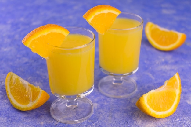 青い背景の上の小さなグラスにオレンジジュースとウォッカ