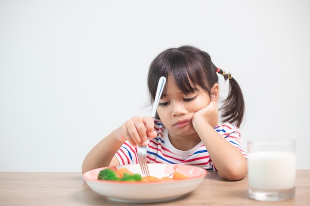 Voeding gezonde eetgewoonten voor kinderen concept Kinderen eten niet graag groenten Klein schattig meisje weigert gezonde groenten te eten
