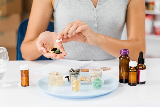 Foto voedingsdeskundige houdt verschillende voedingssupplementpillen in haar handen en schrijft recept voor dagelijkse inname van tabletten voor cliënt voor gezondheidszorg