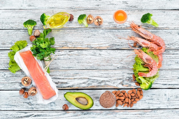 Voedingsmiddelen die omega-3 vitamine bevatten Gezonde voeding avocado's vis garnalen broccoli vlas noten eieren peterselie bovenaanzicht vrije ruimte voor uw tekst op een witte houten achtergrond