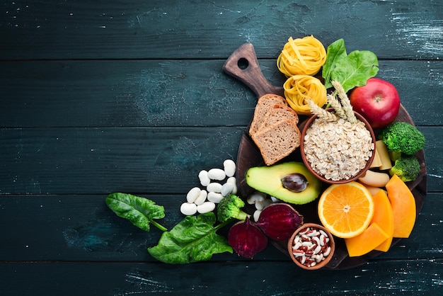 Voedingsmiddelen rijk aan koolhydraten brood pasta avocado meel pompoen broccoli bonen spinazie Het concept van gezond eten Op een zwarte achtergrond