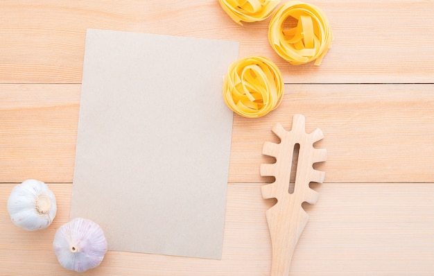 Voedsel achtergrond voor smakelijke Italiaanse gerechten met blanco pakpapier en vintage pasta pollepel op houten achtergrond.