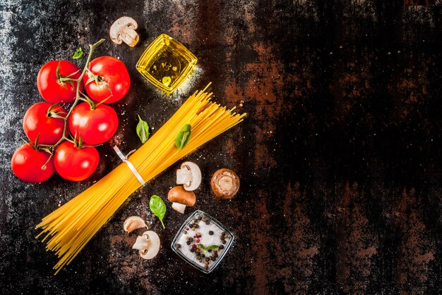 Voedsel achtergrondingrediënten voor het koken van diner. De groentensauzen van deegwarenspaghetti en specerijendonkere roestige achtergrond