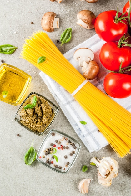 Voedsel achtergrondingrediënten voor het koken van diner. Pasta groenten groenten sauzen en specerijen grijze stenen achtergrond