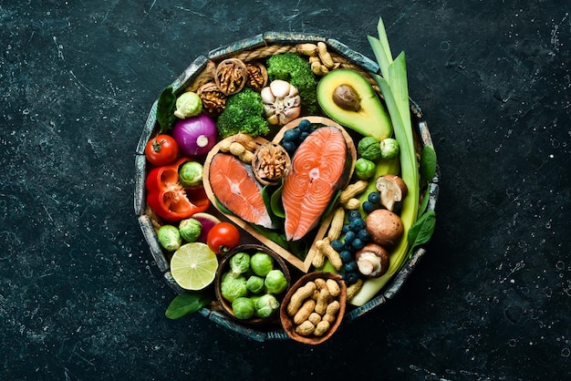 Foto voedsel banner gezonde voeding laag in koolhydraten voedsel voor de gezondheid van het hart zalm avocado's bosbessen broccoli noten en champignons op een zwarte stenen achtergrond bovenaanzicht