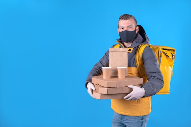 Voedsel bezorger met een medisch masker in een geel jasje