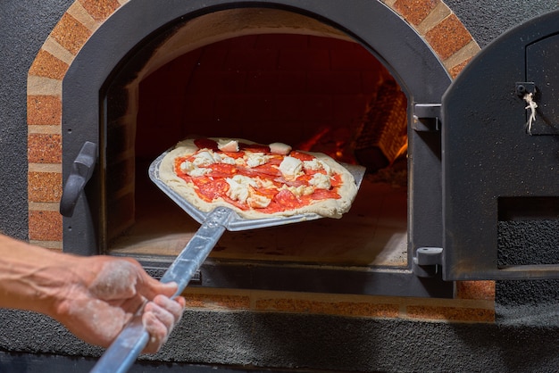 Voedsel concept. Traditionele Italiaanse pizza bereiden. pizza in de voorkant van de oven.