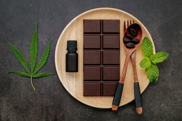 Voedsel conceptueel beeld van cannabisblad met donkere chocolade en vork op donker beton.