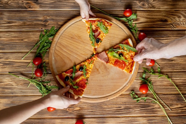 Voedsel eten. Close-up van Mensenhanden die Plakken van Pepperonispizza nemen. Groep Vrienden die Pizza samen delen.