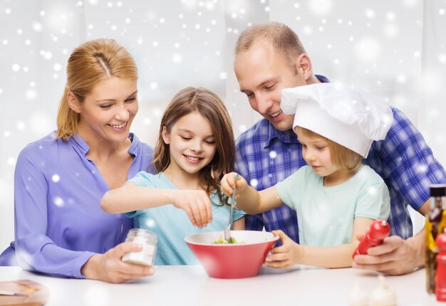 voedsel, familie, kinderen, geluk en mensenconcept - gelukkig gezin met twee kinderen die thuis salade maken voor het avondeten