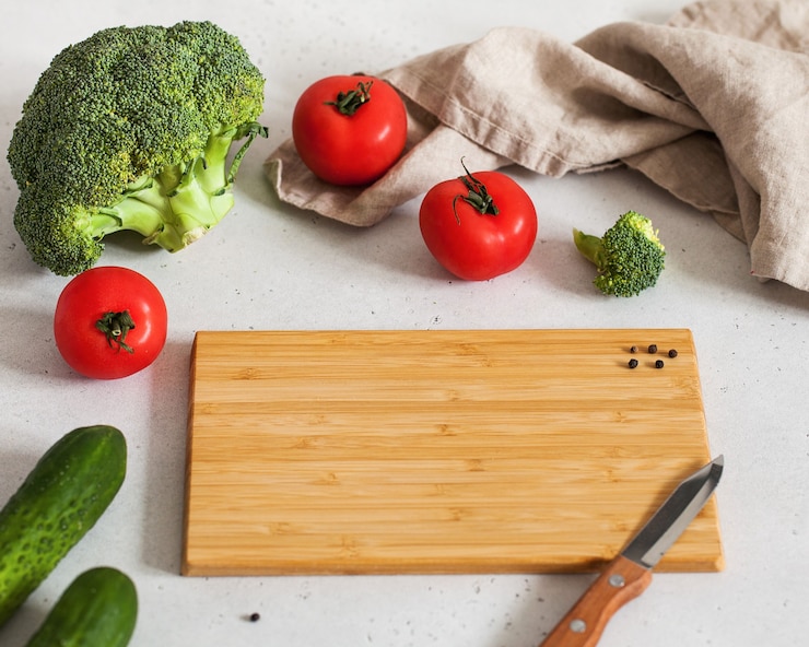Voedsel foto met lege snijplank voor tekst met een mes tomaten, broccoli en komkommers