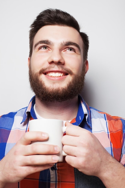 Voedsel geluk en mensen concept jonge baarde man met een kop koffie tegen grijze achtergrond