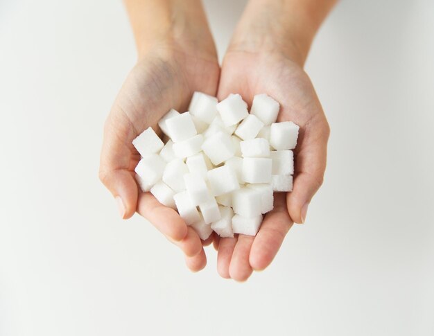 voedsel, junkfood, diabetes en ongezond eten concept - close-up van witte forfaitaire suiker in handen van de vrouw