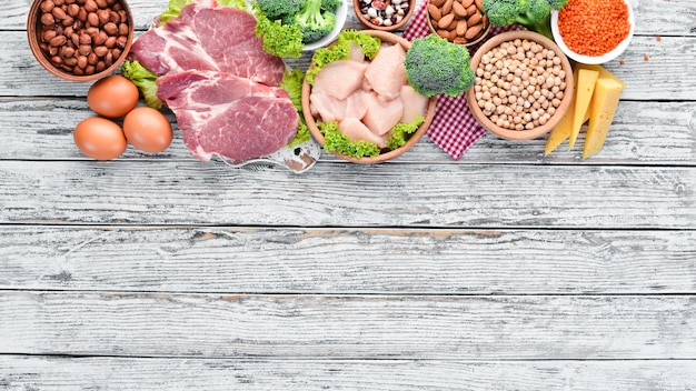 Voedsel met een hoog eiwitgehalte op tafel Vlees kipfilet broccoli bonen kaas eieren tarwe Op een witte houten achtergrond