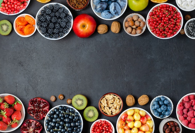 Voedsel met een hoog gehalte aan antioxidanten: bessen, noten, fruit. Zwarte concrete achtergrond. Kopieer ruimte.