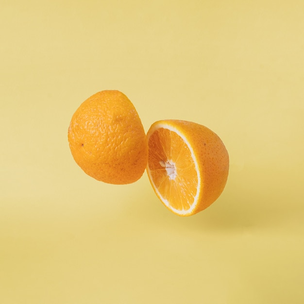 Voedsel met vitaminen tropisch oranje vliegen over pastel gele achtergrond. Vegetarische biologische voeding