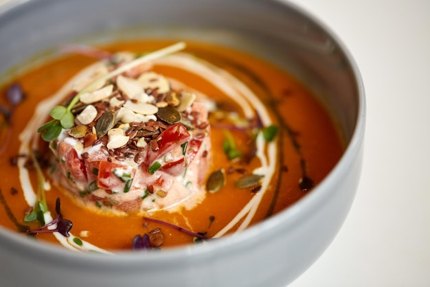 voedsel, nieuwe Noordelijke keuken, culinaire en kookconcept - close-up van groente pompoen-gember soep met geitenkaas en tomatensalade met yoghurt in de kom