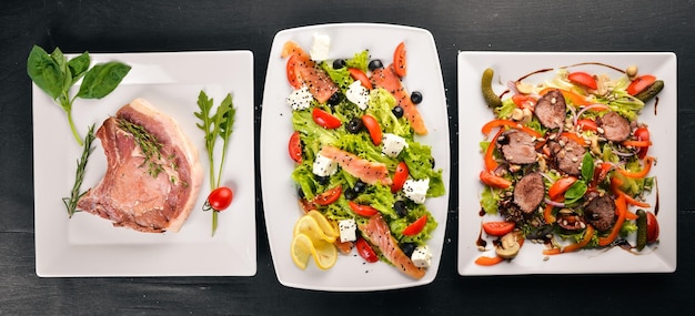 Voedsel Salades van groenten zalm kalfsbiefstuk vlees Op een houten achtergrond Bovenaanzicht Vrije ruimte voor tekst