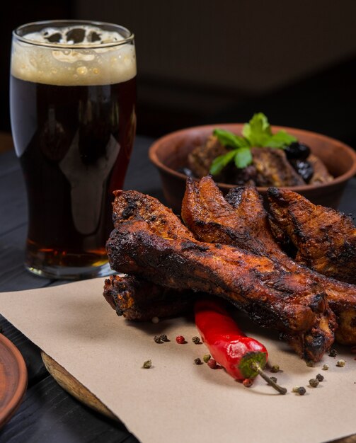 Voedsel set met gegrilde varkensribbetjes glas donker bier op zwarte houten achtergrond