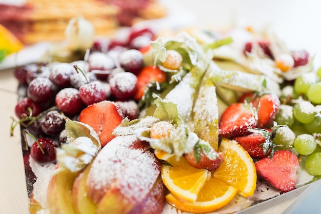 voedsel, snoep en vakantieconcept - sluit omhoog van schotel met gesuikerd fruitdessert