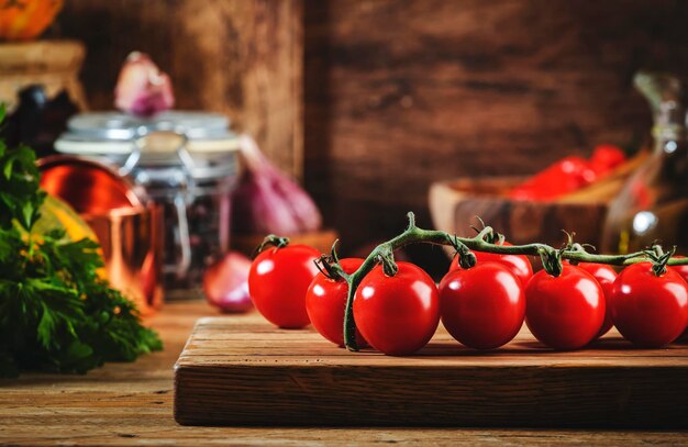 Voedselachtergrond koken met tomaten, pompoenen, kruiden op rustieke houten keukentafel met gietijzeren pankruidenmolens, snijplank, specerijen en kruiderijen, opslagpotten