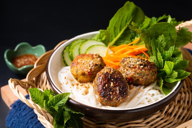 Voedselconcept bun cha vietnamese rijstnoedels en gehaktballen met groenten en kruiden op zwarte achtergrond met kopieerruimte