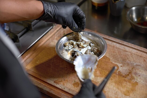 Voedselconcept De chef-kok sprenkelt meel Verse oesters om in de keuken te roosteren Het proces van het koken van spaghetti met zeevruchten