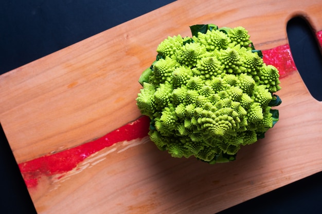 Voedselconcept Verse biologische Romanesco-broccoli op een houten bord op zwarte achtergrond met kopieerruimte