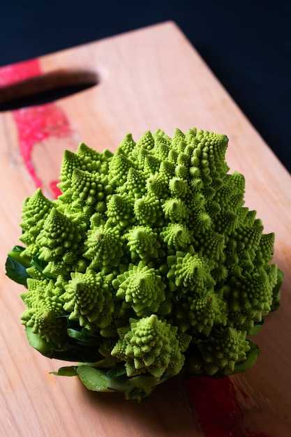 Voedselconcept Verse biologische Romanesco-broccoli op een houten bord op zwarte achtergrond met kopieerruimte