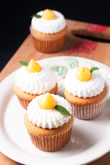 Foto voedselconcept zelfgemaakte biologische citroen meringue cupcakes op een houten bord en zwarte achtergrond met kopie ruimte