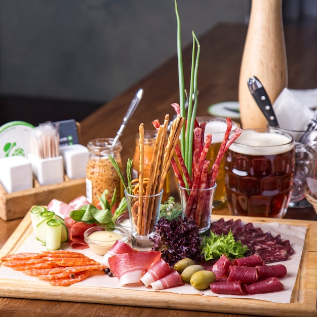 Voedseldienblad met heerlijke salami, stukjes gesneden ham en worstjes. Snijden worst en gezouten vlees op een feestelijke tafel.