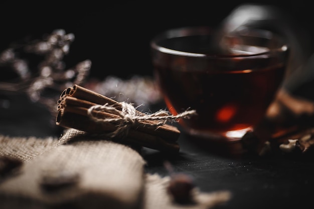Voedselfotografie Kaneel vastgebonden met touw op jute Een glazen kop hete thee op een donkere achtergrond