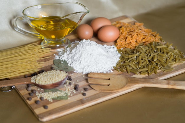 Voedselingrediënten, pasta, meel, olie op een houten bord