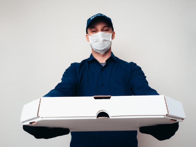 Foto voedselleverancier met blauw shirt, kamp, masker en handschoenen in de covid-19 pandemie.