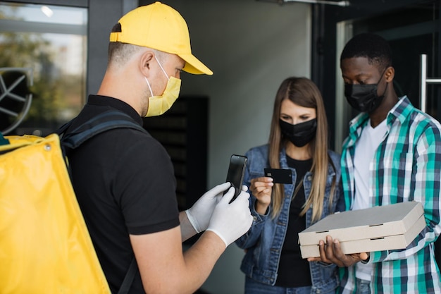 Voedsellevering aan een mooie blanke vrouw met Afrikaanse echtgenoot in gezichtsmaskers