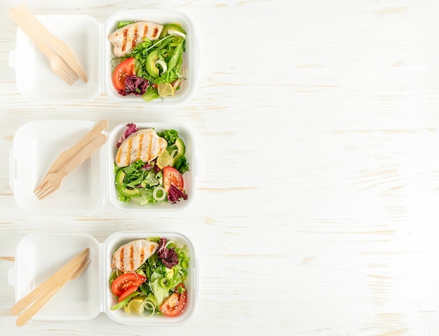 Voedsellevering van lunchboxen met salade op witte houten achtergrond Kopieer ruimte