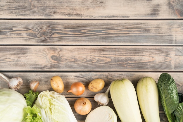 Voedselsamenstelling van ui, kool, courgette, pompoen, merg, knoflook, groenten op houten achtergrond Boerderij produceren