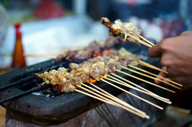 Foto voedselverkoper die satay kookt op de indonesische straatvoedselmarkt